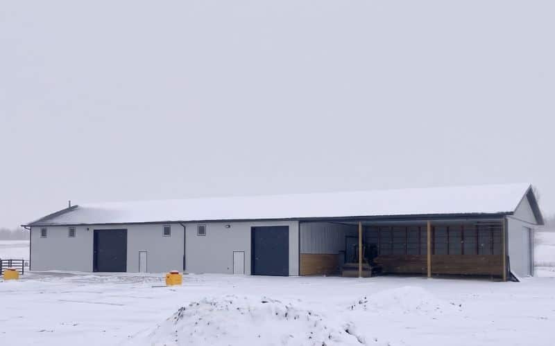A white white post-frame equestrian livestock shelter/barn