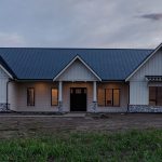 A white white post-frame residential Homestead with wainscoting and a overhead door
