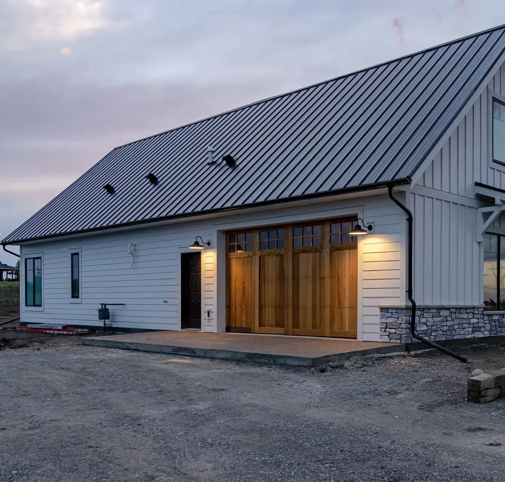 A white white post-frame residential Homestead with wainscoting and a overhead door