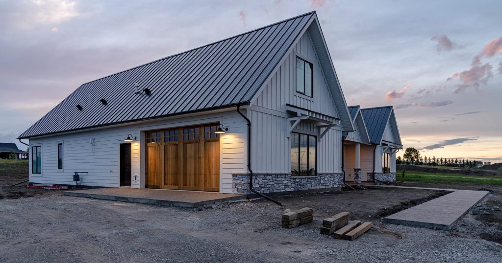 A white white post-frame residential Homestead with wainscoting and a overhead door