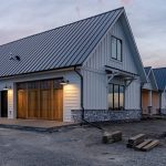 A white white post-frame residential Homestead with wainscoting and a overhead door
