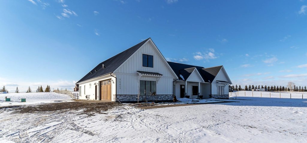 A white white post-frame residential Homestead with wainscoting and a overhead door