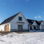 A white white post-frame residential Homestead with wainscoting and a overhead door